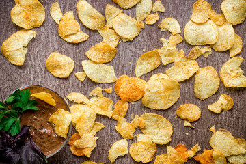 Potato chips with dipping sauce on a wooden table. Unhealthy food on a wooden background.