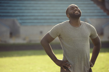 A handsome black man is feeling happy and relaxed, resting after workout in the field
