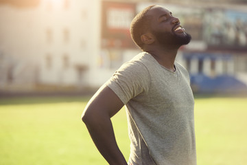 A handsome black man is feeling happy and relaxed, resting after workout in the field