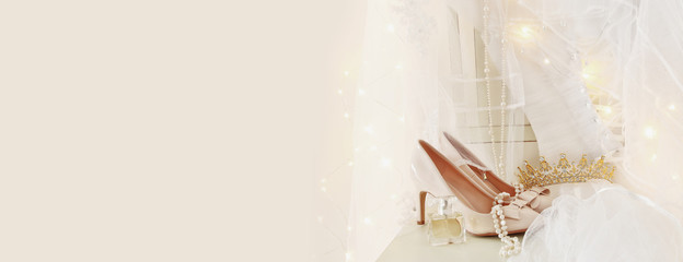 Beautiful white wedding dress and veil on chair with gold garland lights © tomertu