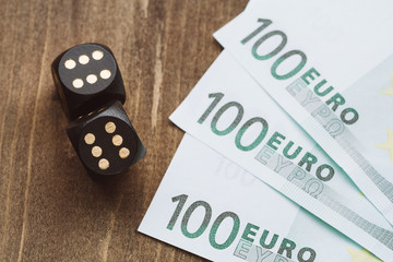 Gambling for money. Black dice and euro on a wooden table.