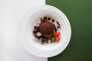 Chocolate fondant on contrast colorful background of white and green. Delicious dessert with...