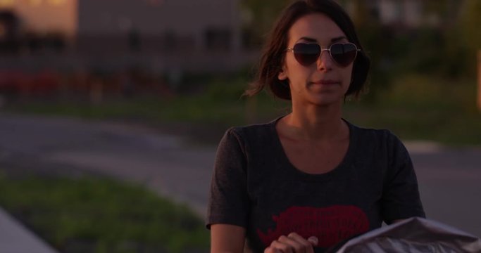 Hip stylish young mom walking baby boy on sidewalk at sunset - close up on face