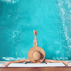 Back view of woman in straw hat relaxing in turquoise swimming pool at luxury villa resort. Summer holiday idyllic background. Vacations Concept. Exotic Paradise.