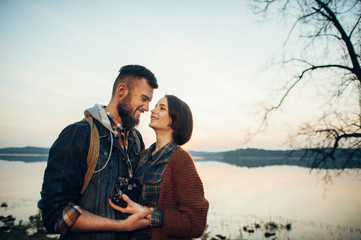 Fototapeta premium man and woman standing with canoe and paddle on coast of lake in sunny morning