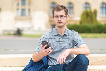 Young man sitting on the stairs with his phone
