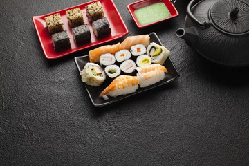 Sushi set and black teapot on black table