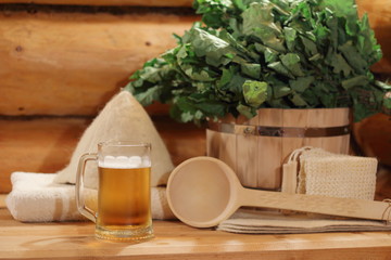 A mug of light beer and bath accessories are in the interior of the Russian bath. A mug of light...