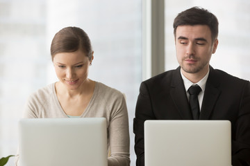 Inquisitive curious businessman with bad manners sneakly looking at laptop screen of businesswoman...
