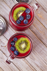 Berry kiwi smoothie in the jars, garnished with blueberries and kiwi. View from above, top studio shot