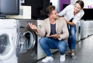 Positive customers looking at laundry machine
