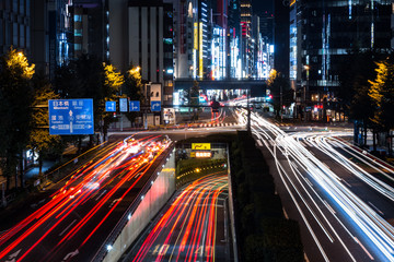 Fototapeta na wymiar Busy crossroad in Tokyo at night long exposure red light traces tunnel dark illumination