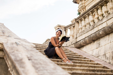 Attractive girl sitting on stairs and reading book.
