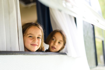 Children are looking through caravan or camper motorhome window.