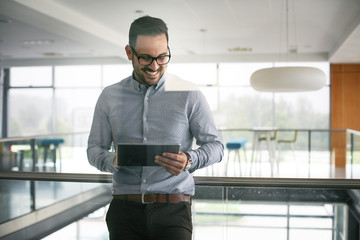 Business man standing in business building. Business man  working on digital tablet.