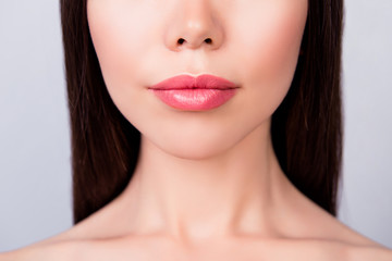 Plastic surgery concept. Lips filling, ideal and perfection mania. Cropped close up photo of young brunette woman`s lips on light background