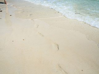 Woman walks on the beach with her footprint on sand.