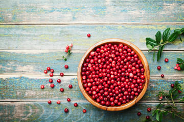 Organic fresh cowberry (lingonberry, partridgeberry, foxberry) in wooden bowl on rustic vintage...