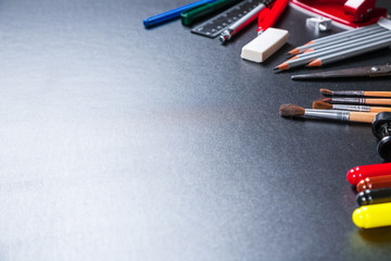 Old blackboard with chalk, stapler, scissors, pencils and stationery. A beautiful backdrop for education, a free space for your text. Back to school.