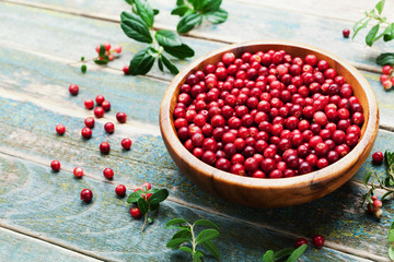 Ripe cowberry (lingonberry, partridgeberry, foxberry) in wooden bowl on rustic vintage background.