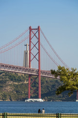 Beautiful view of the red bridge, Ponte 25 de Abril in Lisbon. The bridge connects two cities across the river. Concept of architecture, construction, transportation
