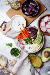 Fresh healthy vegetarian bowl for lunch with baked carrots and red onion, coucous and sliced avocado. Simple and colourful organic food concept. Flat lay overhead view.