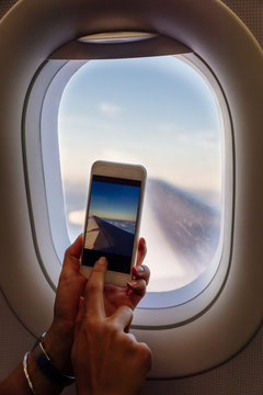 Close up of woman hands taking photo on plane.
