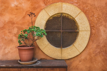 Picture of old round shaped window on the concrete wall with flower on the table