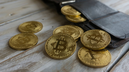 Golden Bitcoins with leather wallet on a wooden table .Close up side view