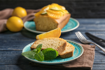Plate with delicious sliced citrus cake and mint leaves on wooden table