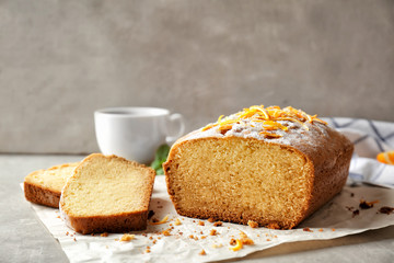 Delicious sliced citrus cake on grey table