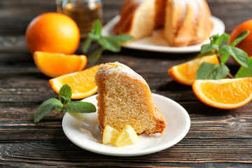 Plate with citrus cake and sliced lemon on wooden table