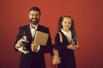 Kid and dad hold microscope, book and stationery