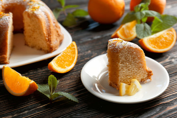Plate with cake and sliced citrus fruits on wooden table