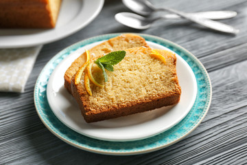 Plate with delicious sliced citrus cake on wooden table