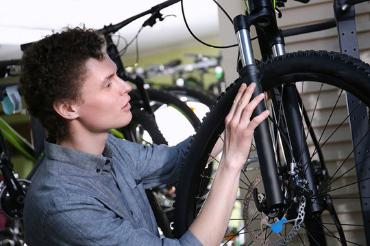 Young man choosing bicycle in shop