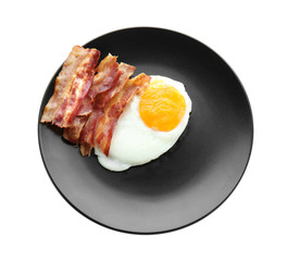 Plate with fried egg and bacon on white background