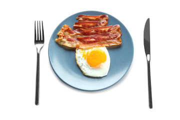 Plate with fried egg, bacon and cutlery on white background