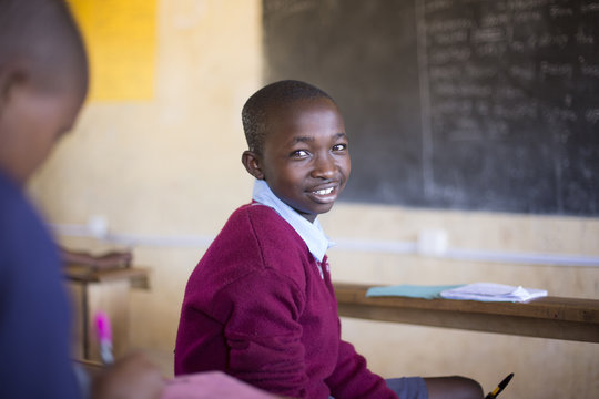 Portrait of smiling school boy in classroom. Kenya, Africa.