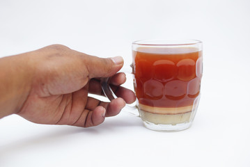 Hand Holding A Glass Of Tea With Milk Over White Background