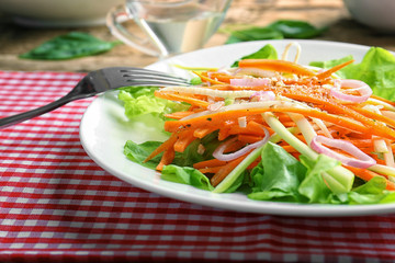 Plate with delicious carrot salad on table, closeup