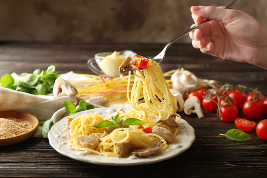 Hand of woman eating delicious turkey tetrazzini