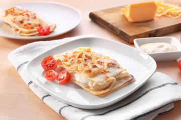 Composition with tasty lasagna, cheese and tomatoes on wooden table