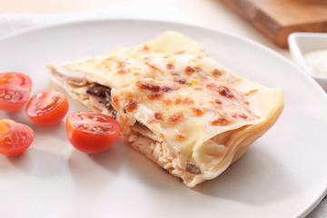 Plate with tasty lasagna and tomatoes on table