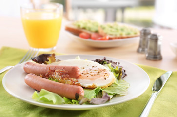 Plate with homemade fried egg, sausages and mix salad on table
