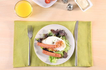 Plate with homemade fried egg, sausages and mix salad on table