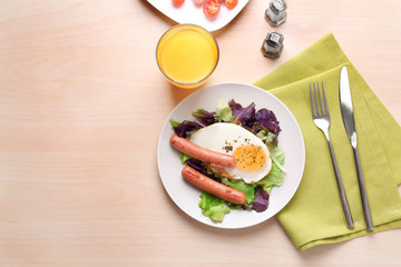 Plate with homemade fried egg, sausages and mix salad on table