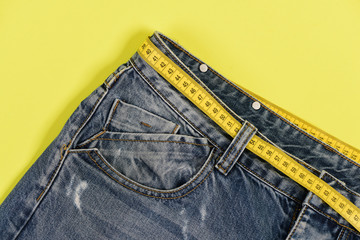 Healthy lifestyle and dieting concept: denim trousers with measure tape