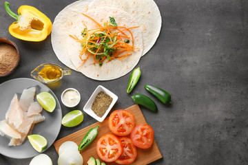 Fish taco with filling and ingredients on grey background