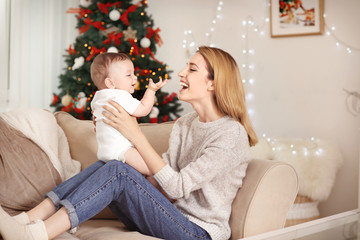 Happy young mother with baby in decorated room for Christmas